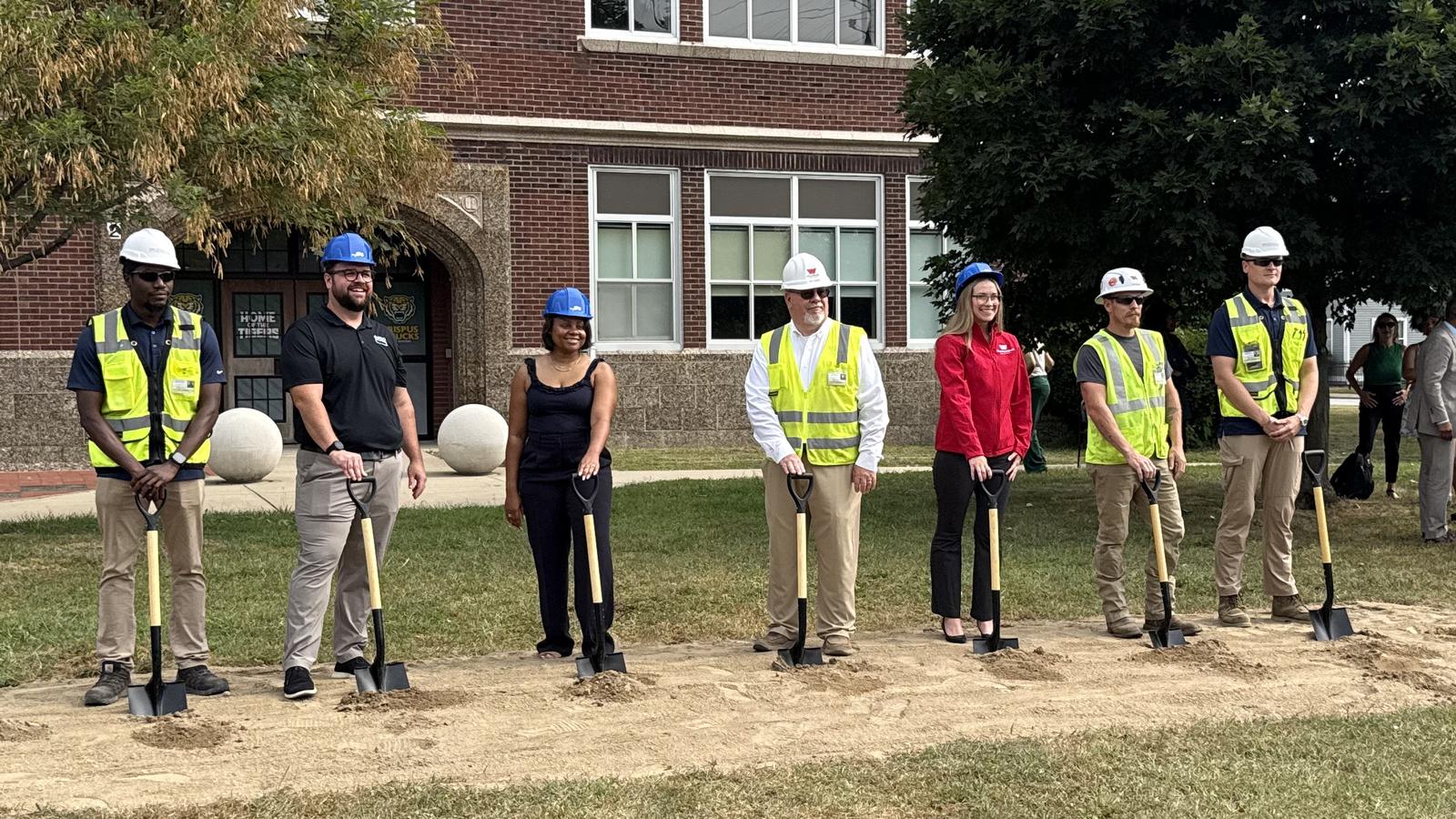Members of the project team stand with ceremonial shovels in front of Crispus Attucks High School ahead of the dig.